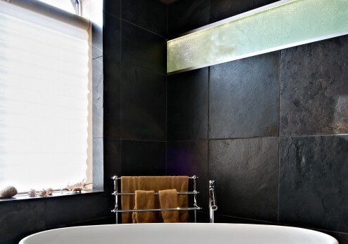 A slate-tiled bathroom with a large tub.