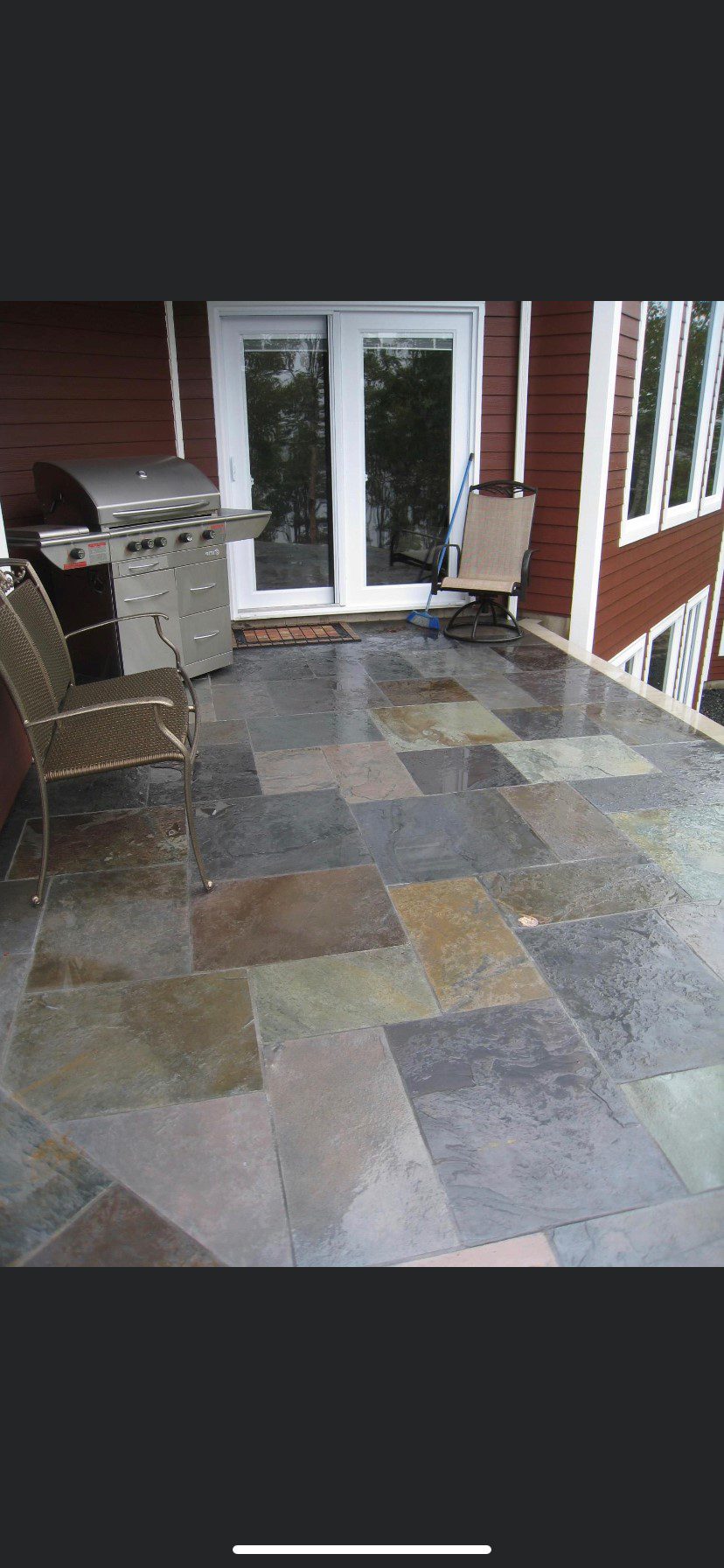 A patio with a grill and scotia stone chairs.